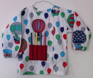 blouse de peinture terminée fermée par un velcro avec  gros crayons dans la poche rouge